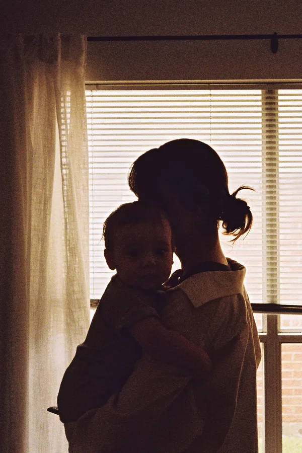 Alicia holding her child by a sunny window